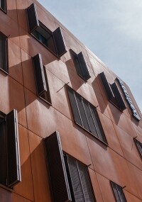 Aluminium-Faltschiebeläden mit Rosteffekt schaffen ein lebendiges Fassadenspiel